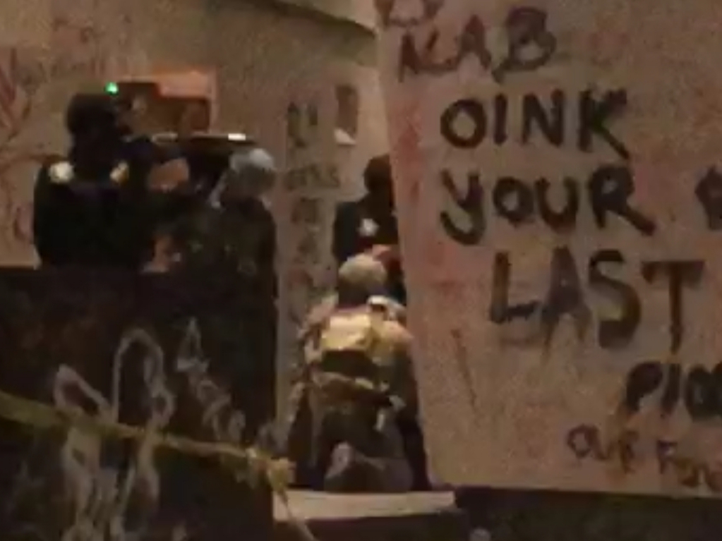 Police and marshalls arresting someone in front of graffiti