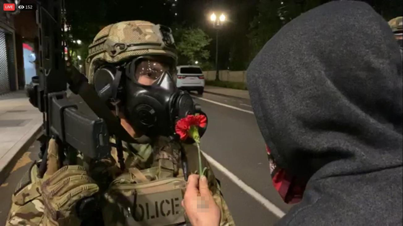 Protestor offering a flower to officer